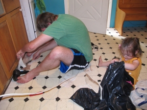 Josh ripped up the old linoleum and Evee put the pieces in the trash bag